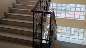 A staircase with a metal railing and beige steps leading to a second floor.