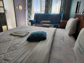 Une chambre d’hôtel avec un lit, une chaise bleue et une tête de lit en bois.