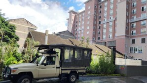 A beige SUV parked in a residential area with a multi-story building in the background.