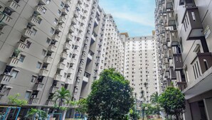 Een hoog appartementencomplex met meerdere balkons en een centrale binnentuin met bomen.