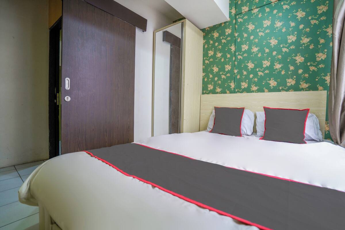 Een hotelkamer met een groot bed, een kledingkast en bloemenbehang.
