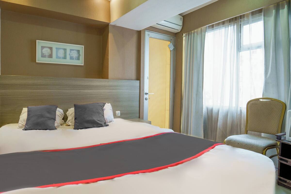 Een hotelkamer met een groot bed, een stoel, een bureau en een raam met gordijnen.