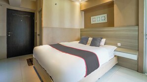 Een moderne hotelkamer met een groot bed, een hoofdbord, een klein nachtkastje en een deur met een kapstok.