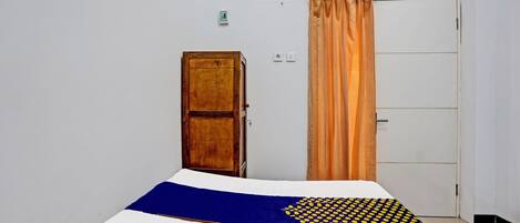 A room with a bed, a wooden door, a white wardrobe, and a curtain.