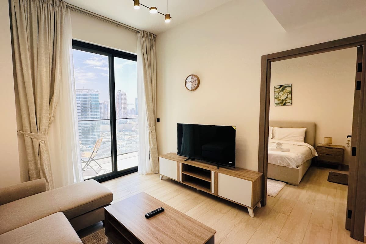 Een moderne hotelkamer met een groot raam, een flatscreen televisie, een bank en een bed.