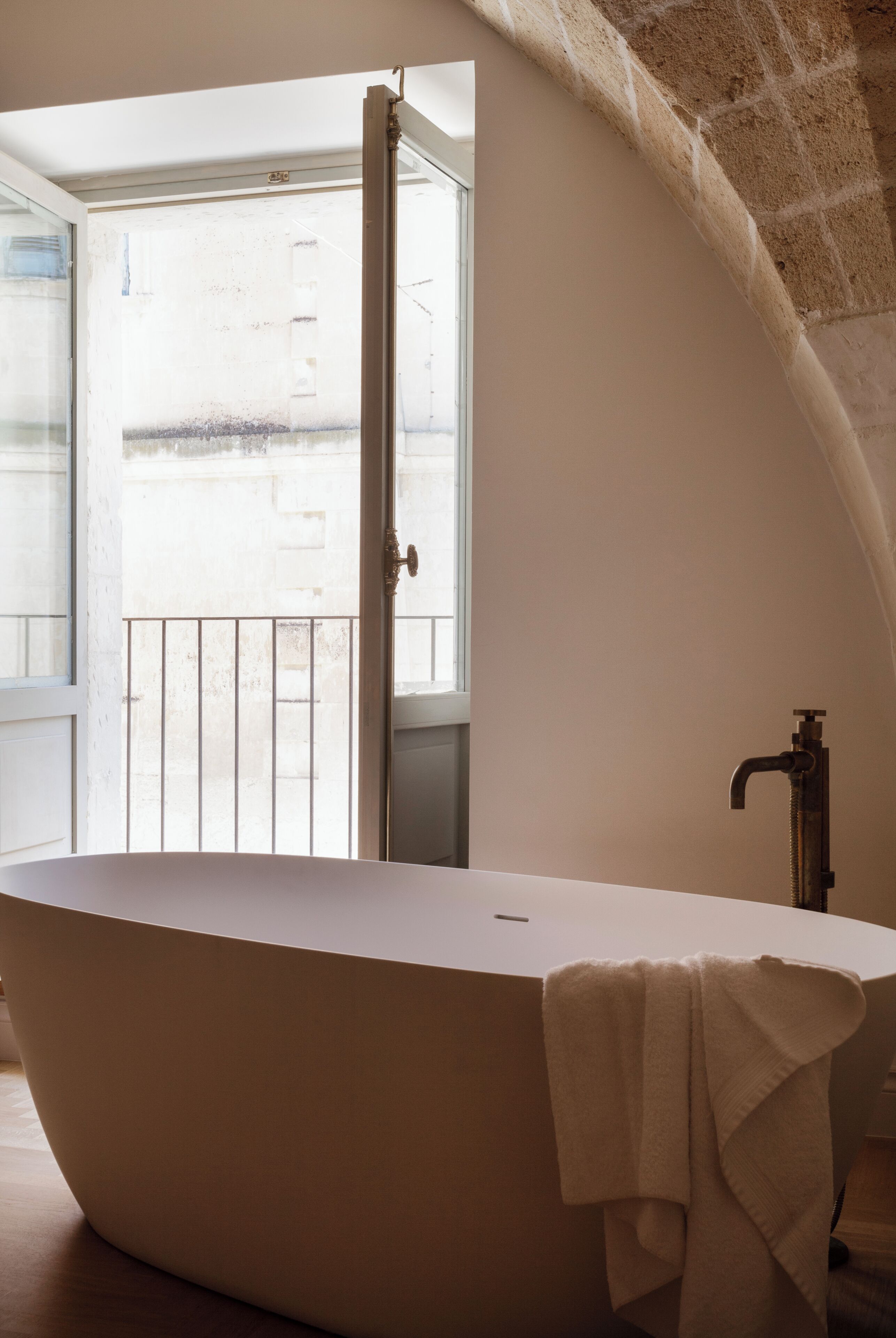 A modern bathroom with a freestanding bathtub, a visible door leading to an outdoor balcony, and a visible window.