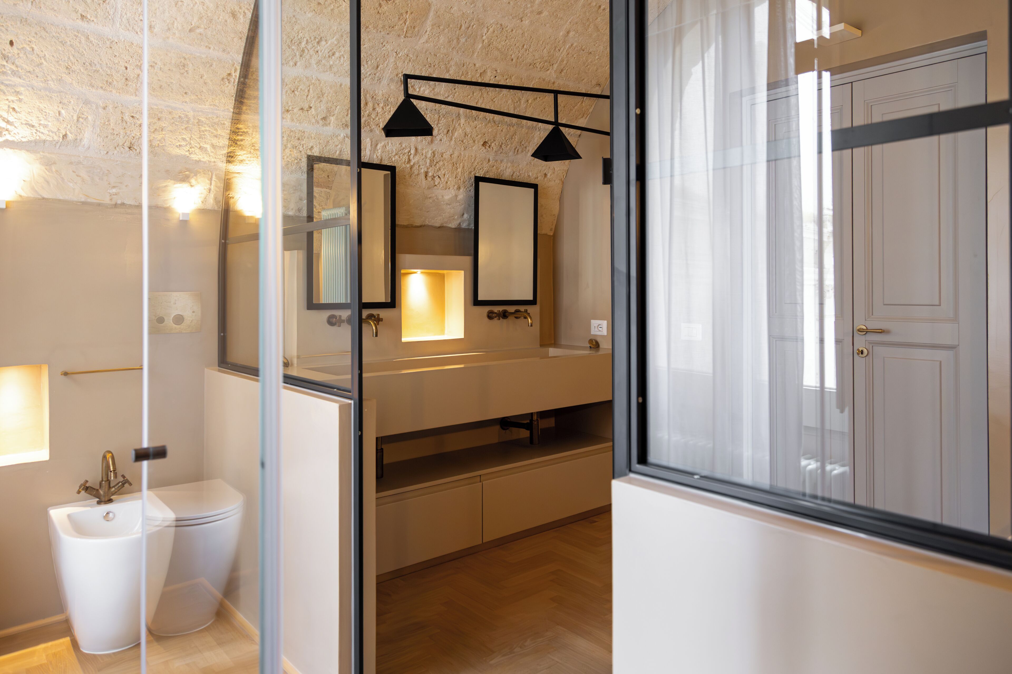 Une salle de bain moderne avec une paroi en verre, des toilettes blanches, un lavabo avec un miroir et un espace douche.