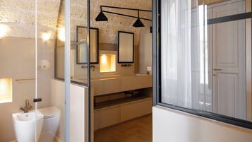 Une salle de bain moderne avec une paroi en verre, des toilettes blanches, un lavabo avec un miroir et un espace douche.