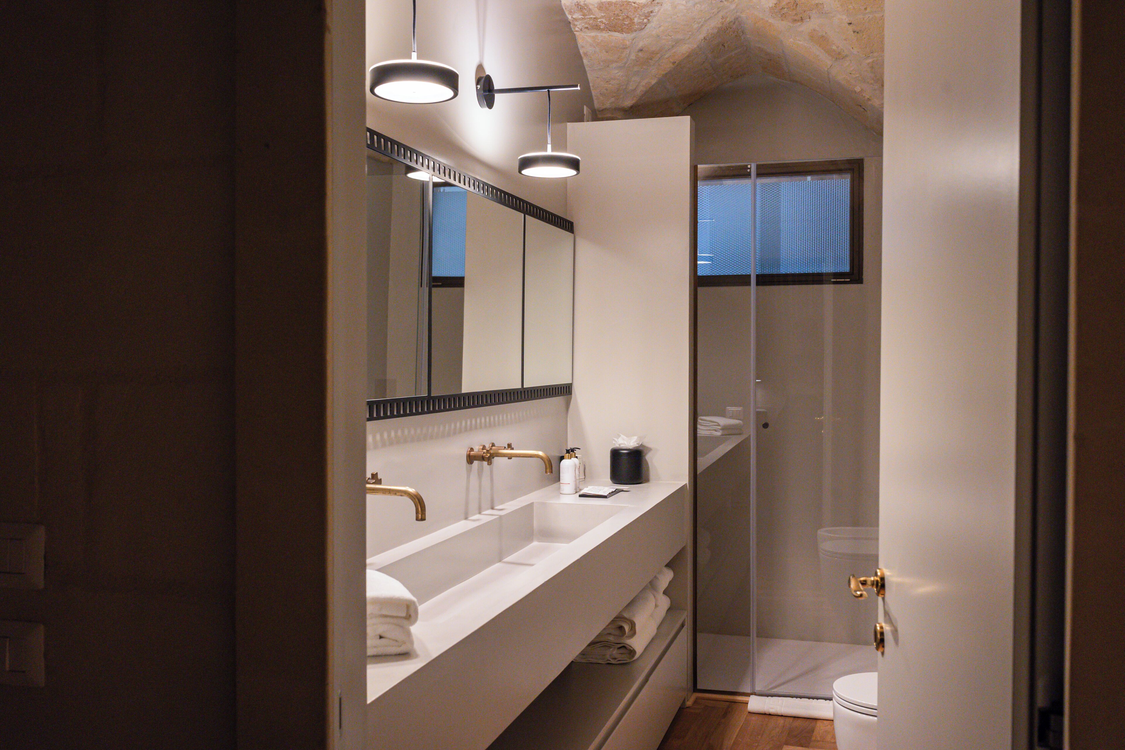 A modern bathroom with a large mirror, dual sinks, and a glass-enclosed shower.