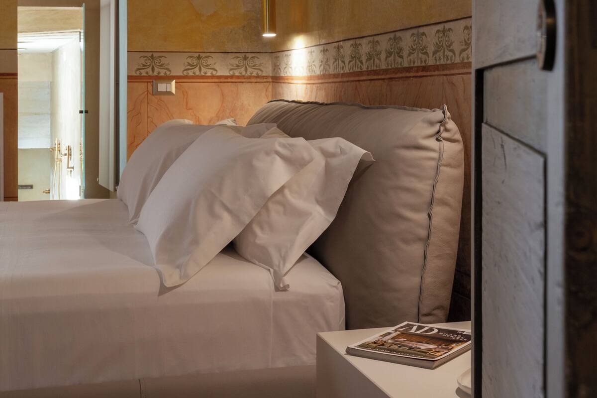 Een slaapkamer met een bed, nachtkastje en een deur.