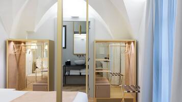 A bedroom with a canopy bed, a vanity with a mirror, a bedside table, and a hanging rack.
