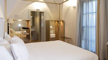 Quarto de hotel com cama grande, espelho, guarda-roupa e janela com cortinas.