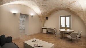 A spacious loft with a high arched ceiling, a dining area with a round table and chairs, and a cozy seating area with a sofa. - Palazzo Zimara Boutique Hotel - The D'Angelo Family Collection (Lecce)