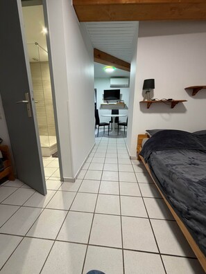 Une chambre à coucher comprenant un lit, un bureau avec une chaise, une télévision et une étagère avec une lampe.