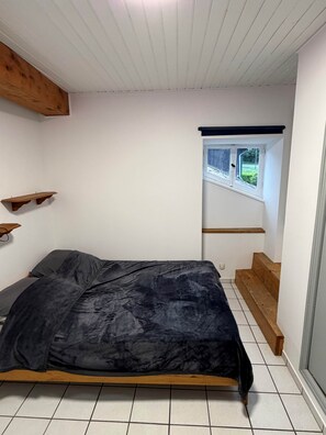 A bedroom with a bed, wooden beams, a window, and a view of greenery outside. - Aurore - Appartement 3 Personnes (Saint-Martin-d'Uriage)