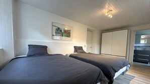 A bedroom with two beds, a wardrobe, and a painting on the wall. - Atacama - Appart. en Rez-de-chaussée (Saint-Martin-d'Uriage)