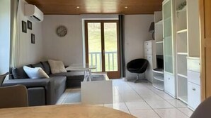 A modern living room with a sofa, a coffee table, and a chair. There is a large window with a view of greenery outside. - Ispahan - Grand Duplex Avec 2 Chambres Indépendantes (Saint-Martin-d'Uriage)