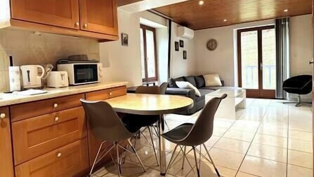 A modern kitchen with wooden cabinets, a dining table with chairs, and a living area with a sofa and a chair. - Ispahan - Grand Duplex Avec 2 Chambres Indépendantes (Saint-Martin-d'Uriage)