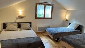 Une chambre avec deux lits, une fenêtre avec des rideaux et un appareil de climatisation.
