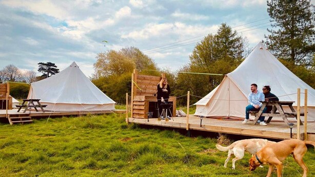 A campsite with two tents, a wooden deck, and a dog. - Walltree House Glamping - Bell Tent (Brackley)