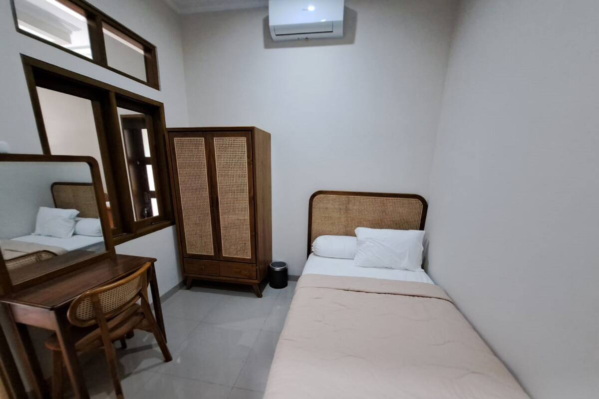 Una habitación pequeña y limpia con cama, escritorio, silla, armario y espejo.