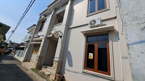 Un bâtiment à deux étages doté d'un balcon, d'une enseigne indiquant un commerce et d'un appareil de climatisation.