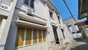 Un immeuble de deux étages doté d’un balcon, d’un appareil de climatisation et d’une fenêtre ornée d’une grille décorative.