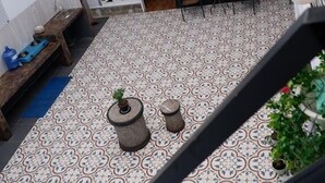 Une cour intérieure à plusieurs niveaux, dotée d’un sol carrelé, d’un banc et de plantes en pot.