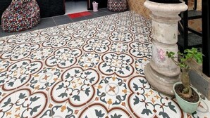 Un vaste espace intérieur doté d’un sol à motifs, d’un escalier agrémenté de plantes et d’un coin salon avec des fauteuils en forme de poire.