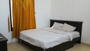 Une chambre à coucher avec un lit, une table de chevet et un rideau.
