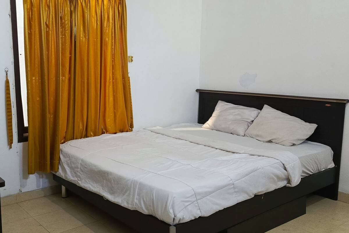 A bedroom with a bed, a nightstand, and a curtain.