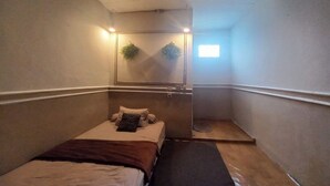 Een kleine, smalle kamer met een bed, een spiegel en een klein raam.