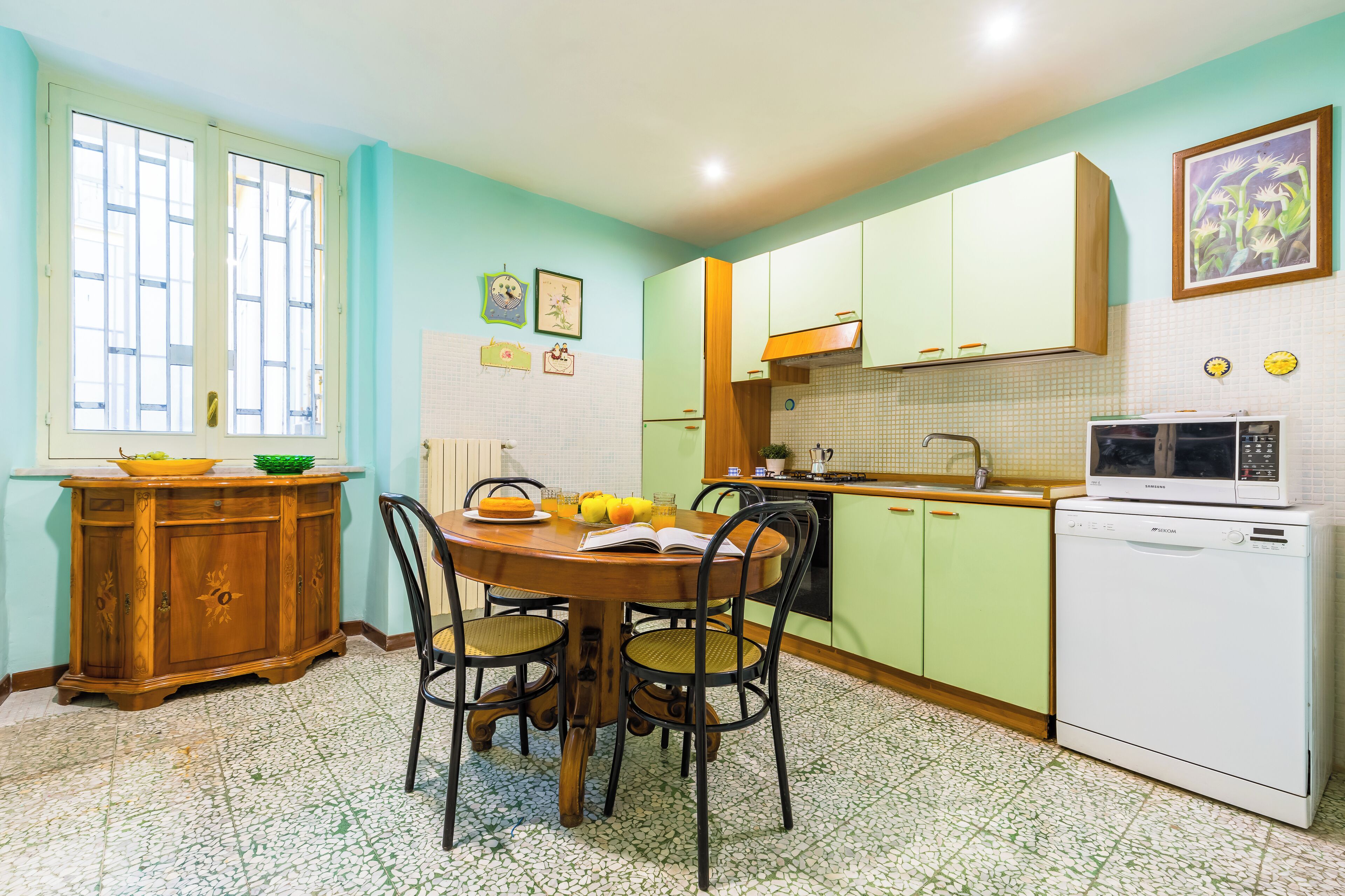 A kitchen with a dining table, chairs, a microwave, and a refrigerator.