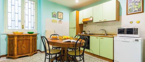 A kitchen with a dining table, chairs, a microwave, and a refrigerator.