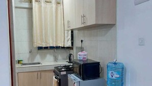 Eine kleine Küche mit Spüle, Herd, Mikrowelle und Kühlschrank.