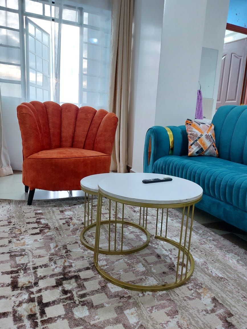 A living room with a round coffee table, a teal sofa, and an orange armchair.