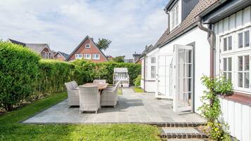 A residential property with a paved patio, outdoor furniture, and a well-maintained garden.