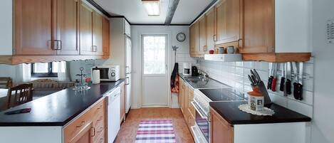 Une cuisine avec des meubles de rangement en bois, un four à micro-ondes, une machine à café et un porte-couteaux.