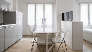 A modern kitchen with white cabinets, a dining table with chairs, and a refrigerator. - A pochi passi dal Mercato delle Erbe by Wonderful Italy (Bologna)