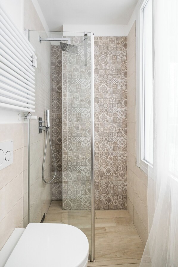 A modern bathroom with a shower, patterned tiles, and a toilet.