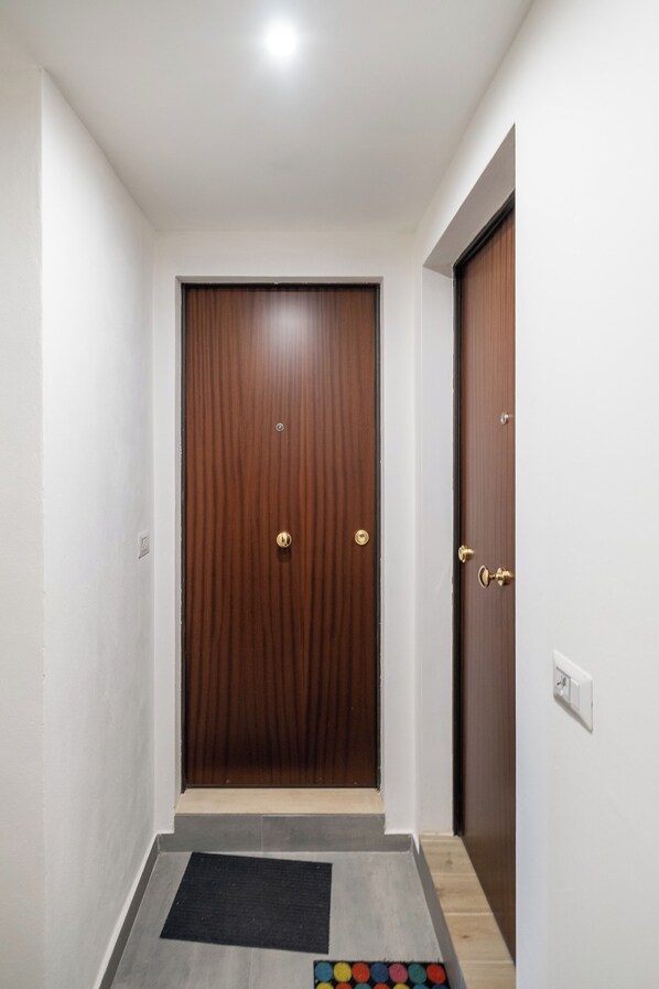 A hallway with a wooden door, a doormat, and a small step leading to a room. - A pochi passi dal Mercato delle Erbe by Wonderful Italy (Bologna)
