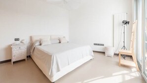 A minimalist bedroom with a large bed, bedside table, and a radiator.