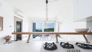 A modern kitchen with a central island, a gas stove, and a view of the outdoors.