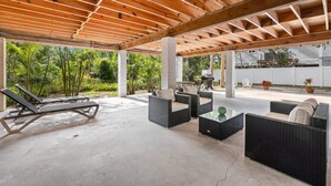 Un patio exterior cubierto con sillones de descanso, mobiliario de mimbre y suelo de hormigón.