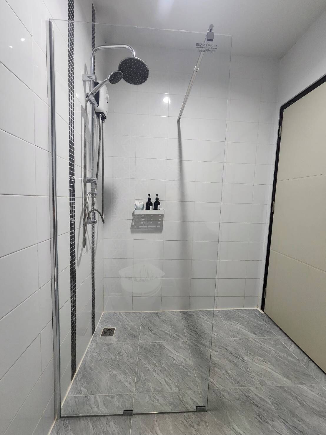 Un espace douche moderne doté d’une porte en verre, d’un pommeau de douche à main, d’un pommeau de douche fixé au mur et d’un panneau de commande.