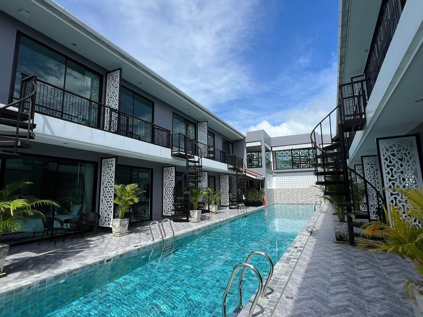 A modern hotel with a swimming pool, outdoor seating, and decorative screens.