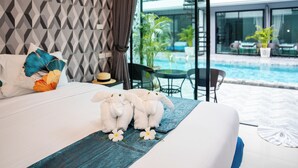 Una habitación de hotel con una cama, vistas a una piscina y un balcón con mobiliario exterior.
