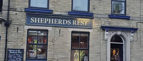 A building with a sign reading "Shepherds Rest" and a car parked in front.