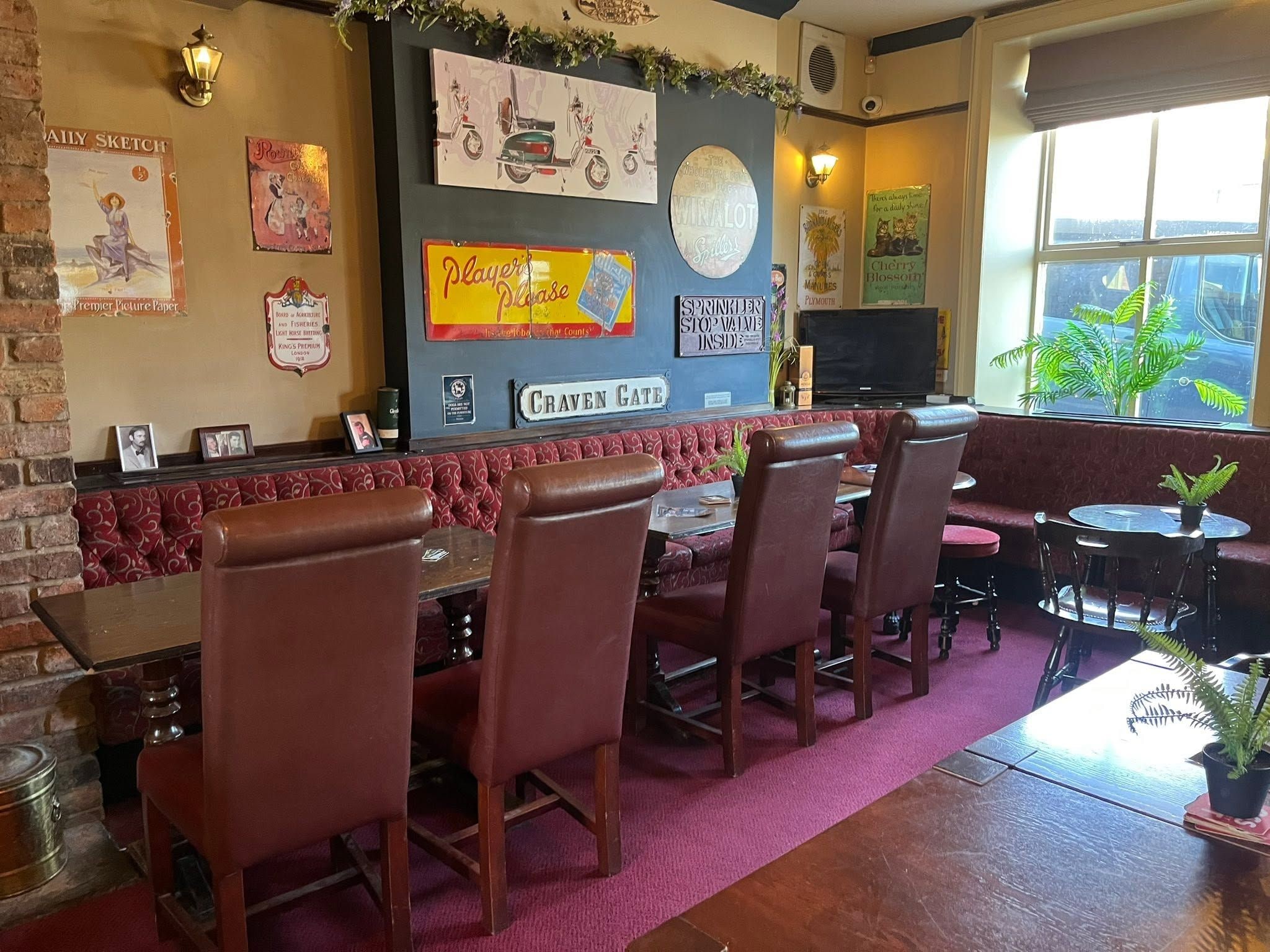 A bar area with leather chairs, a red carpet, and vintage posters on the wall.