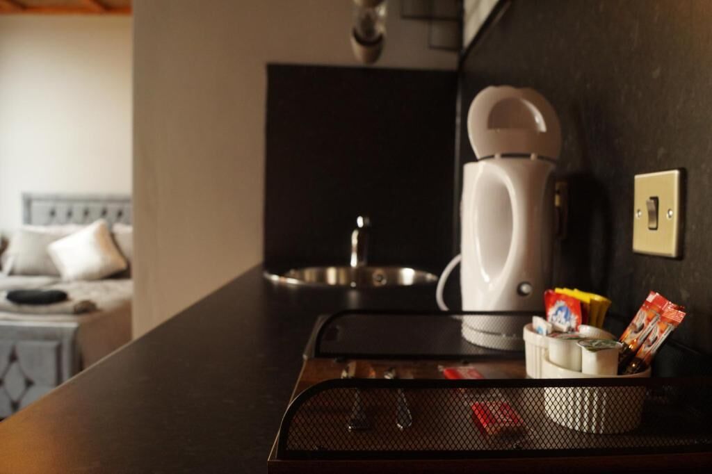 A kitchen area with a coffee maker, a kettle, and a tray with condiments.
